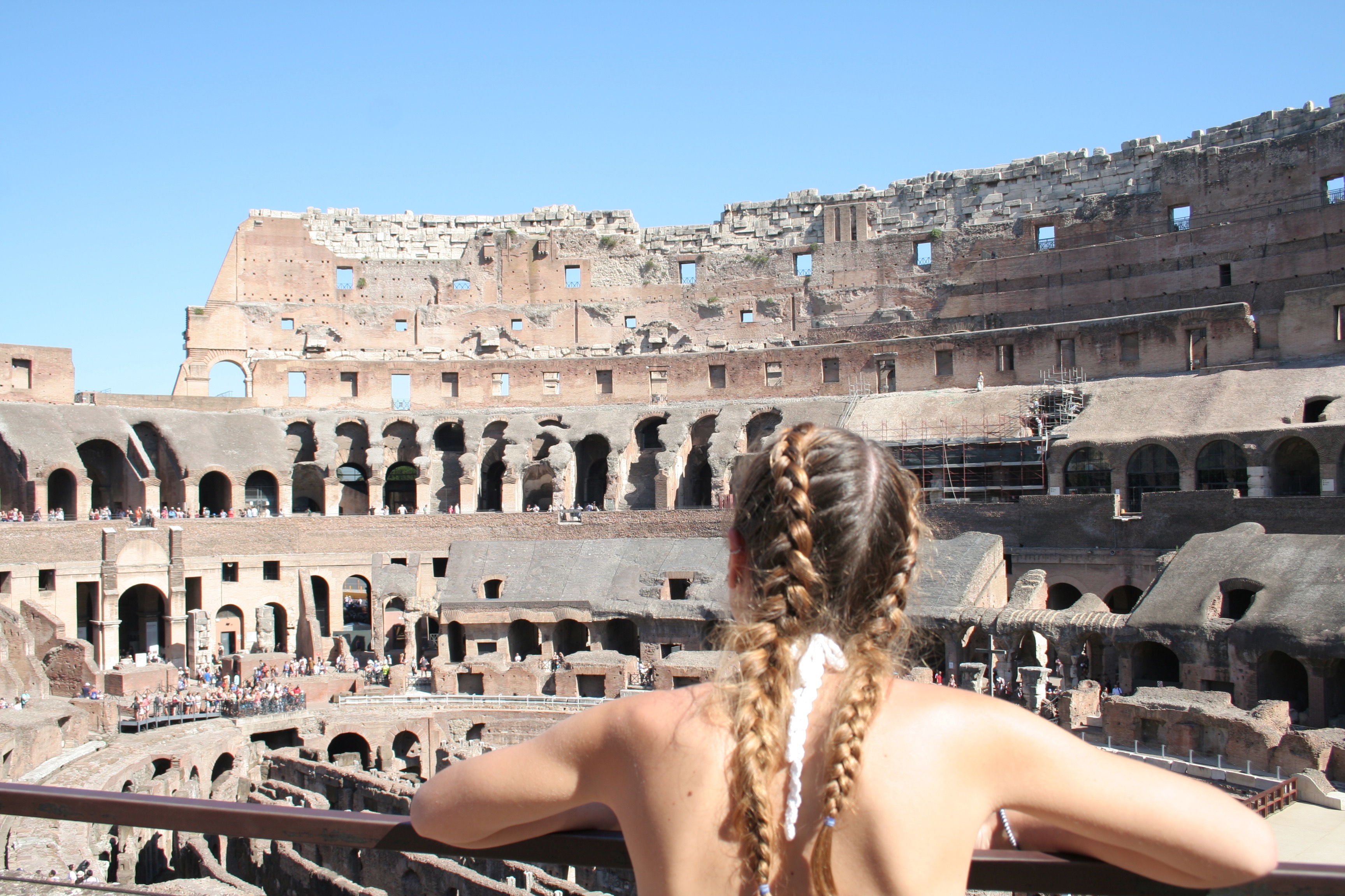 girl learning forward admiring view of colosseum in rome